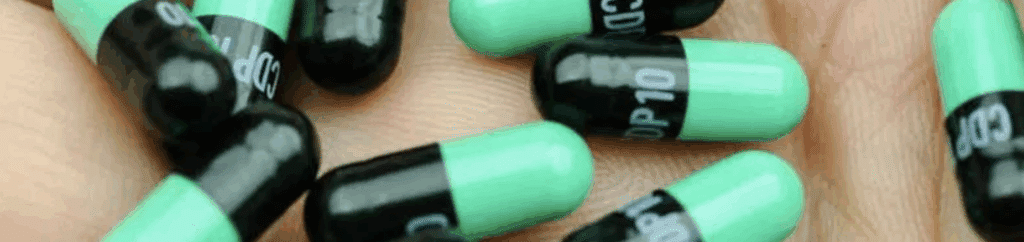 Close-up of green and black Valium capsules in a person’s hand, representing a commonly prescribed and frequently abused benzodiazepine.